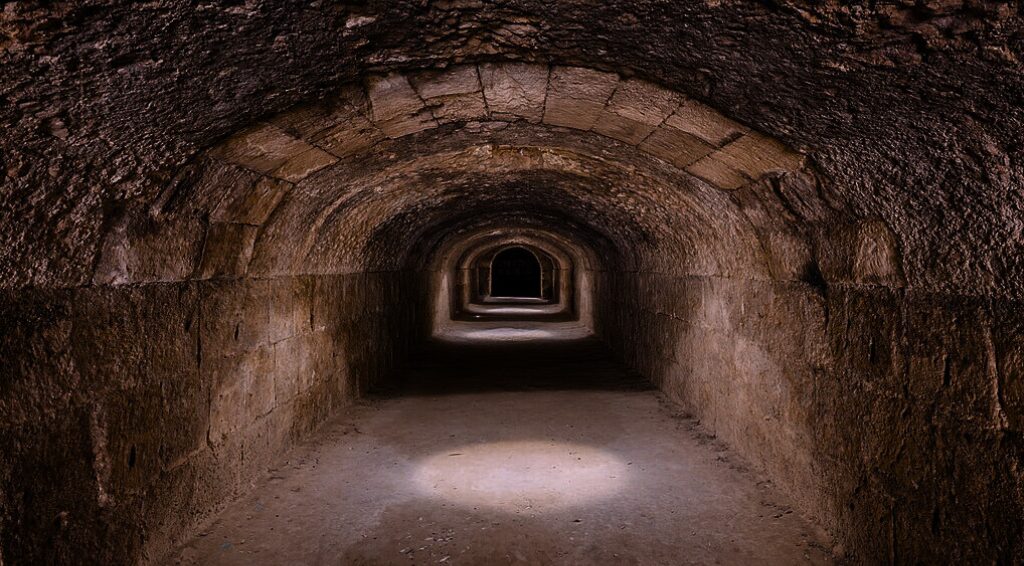 A photo of a dark dungeon corridor descending off into the distance.