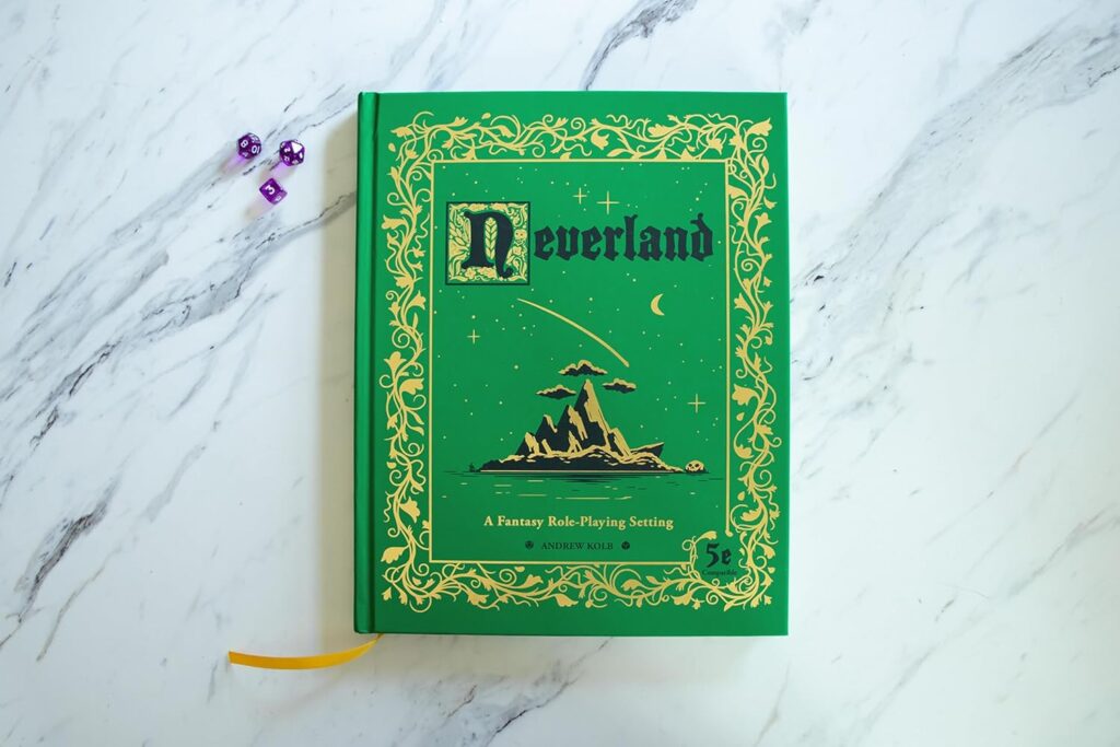 A copy of Neverland 5e setting book sitting on a marble countertop next to some dice. It is a green book with gold inlay and black text, designed in a storybook style.